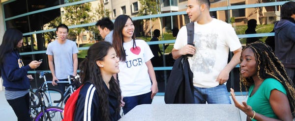 UCR students gather at tables and with bicycles at the Highlander Union Building (HUB)