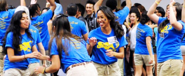 Students wearing blue UCR T-shirts enjoy an indoor group activity